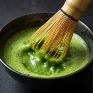 Traditional bamboo whisk chasen mixing premium ceremonial grade matcha in a bowl to create a rich and creamy green foam.