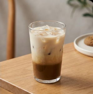 Refreshing iced hojicha latte in a clear glass showing distinct layers of milk and dark roasted tea, perfect for cafe beverage menus.