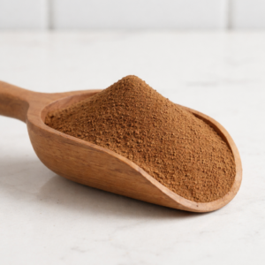 Close-up of rich dark brown signature roasted hojicha powder on a wooden scoop, highlighting its fine texture and deep roasted aroma.
