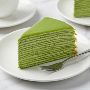 Slice of matcha crepe cake with multiple layers, highlighting the vibrant green color suitable for desserts.