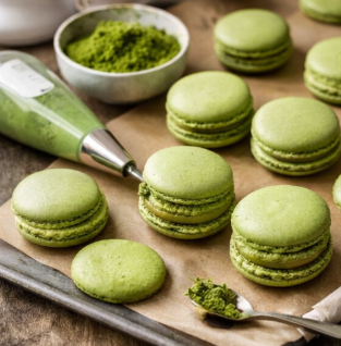 Freshly baked matcha macarons on a tray with piping bag and matcha powder for baking